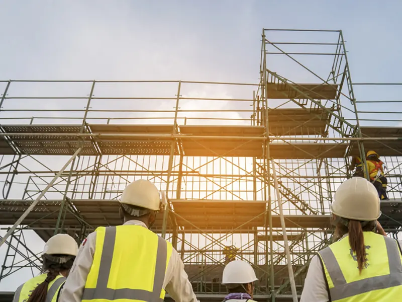 Equipe em obra com andaimes — locação de equipamentos para construção